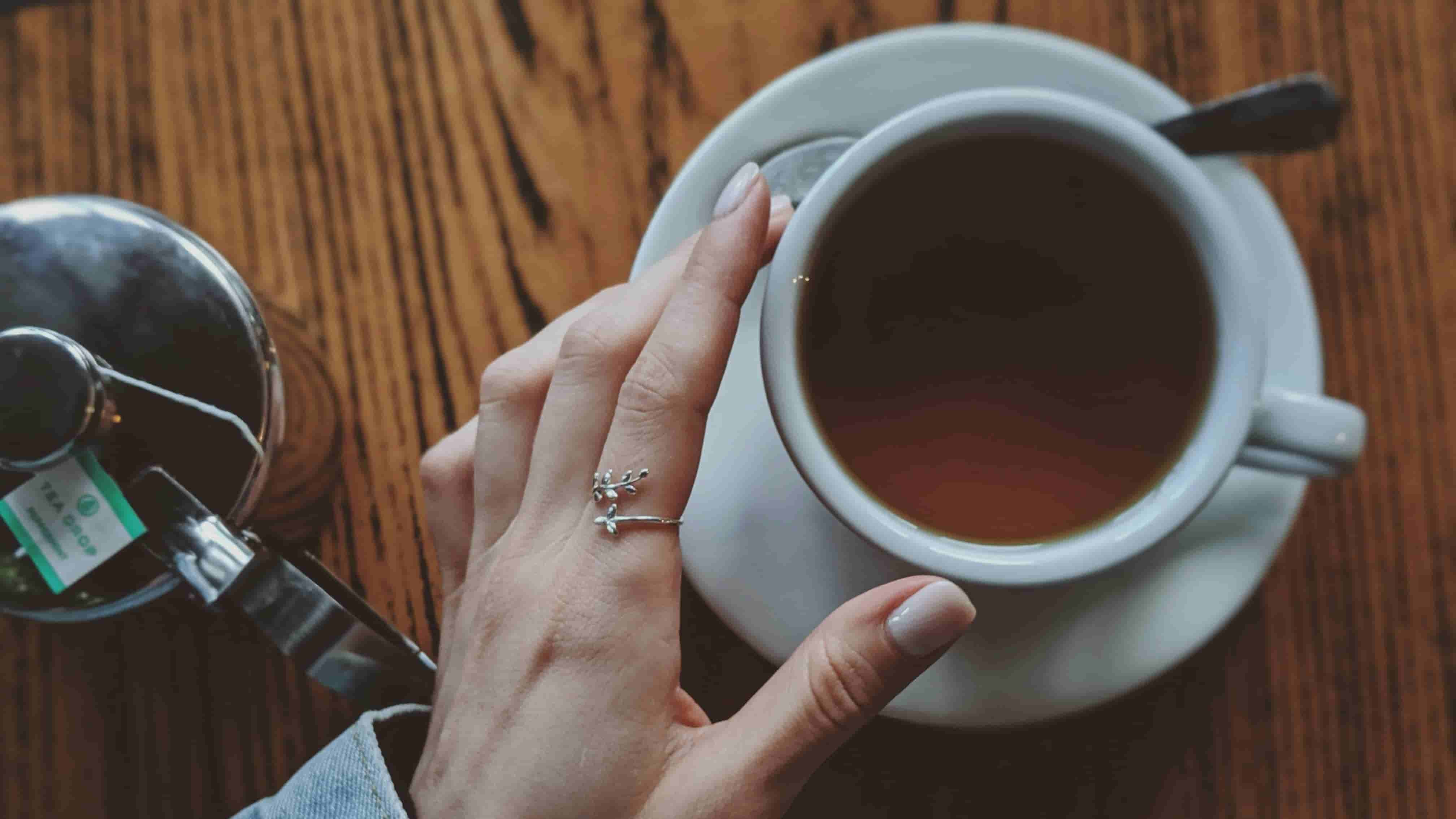 a white cup rose black tea with a hand holding