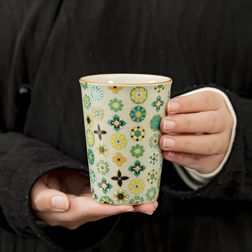Hundred Flowers-style ceramic tea cup held in hand