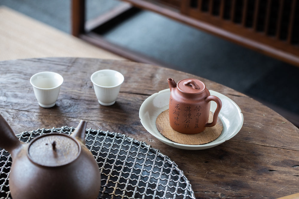 A Chinese teapot and two cups on a wooden table
